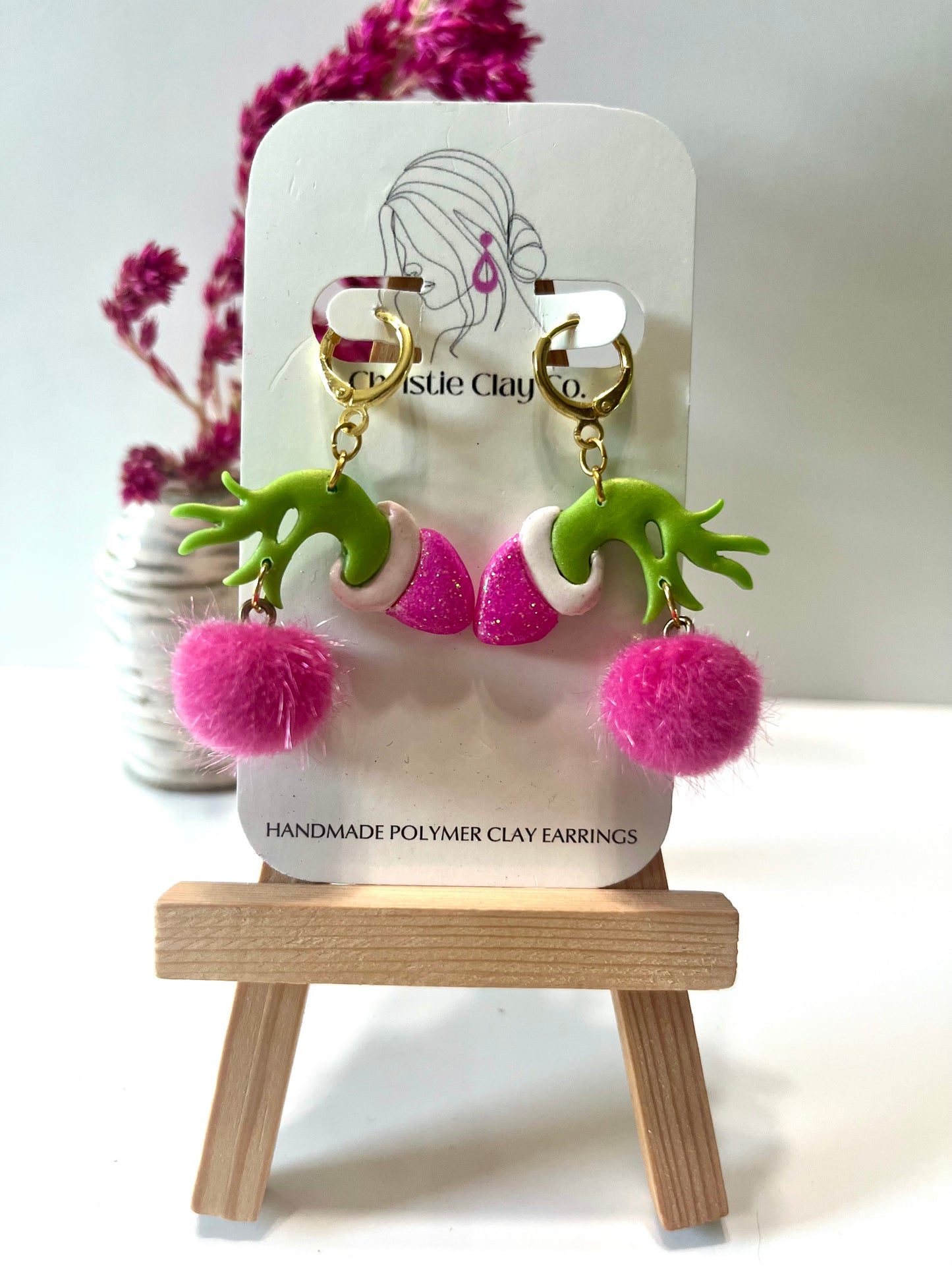 Christmas-Green meanie’s hand holding pink pom-pom